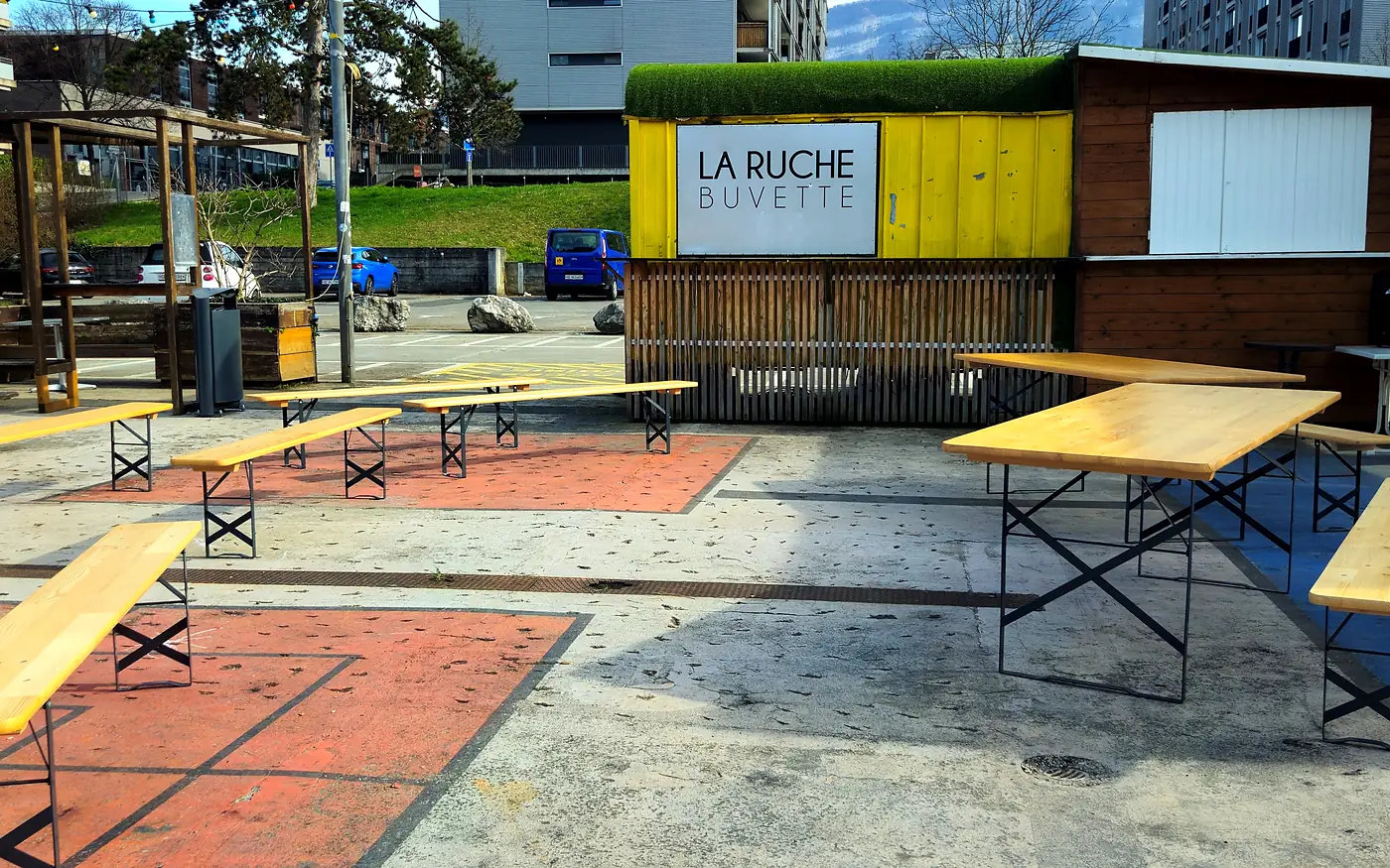 La place de la Tambourine et la buvette jaune La Ruche, tables et bancs vides, en mars 2025