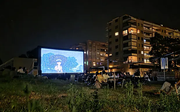 Cinéma en plein air, la foule assise dans l’herbe devant l’écran, août 2025